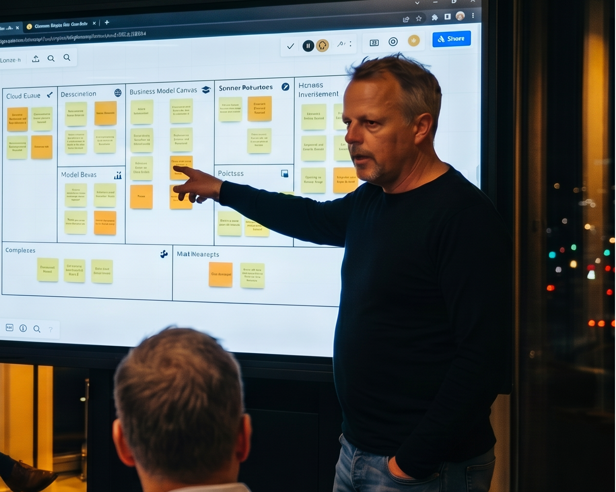 Patrick presenting a digital whiteboard with sticky notes to a small group of colleagues in a modern office room at night.